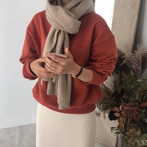 Detail eines beigen Strickschals und orangefarbenen Oversize-Pullovers für den Herbst