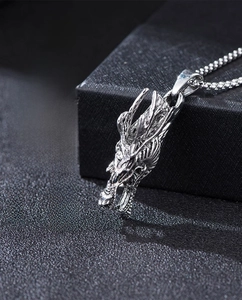 Detailed macro view of a silver dragon head pendant with red stone eyes and steel chain