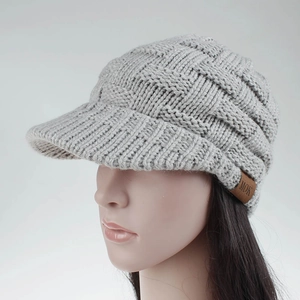 Close-up of grey knitted ponytail baseball cap with a brown leather 'MOK' brand label
