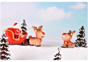 Detail view of miniature Santa Claus in a sleigh with reindeer on snowy landscape