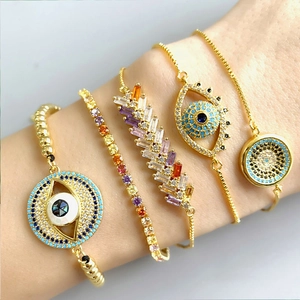Close-up of bohemian gold-plated bracelets featuring colorful evil eye charms and zircons