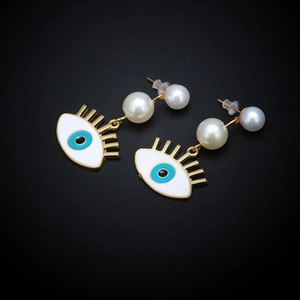 Detailed close-up of gold metal evil eye earrings with white enamel and centered pearl