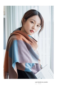 Detailed view of plaid cashmere-like scarf with fringe edges and soft color blocking