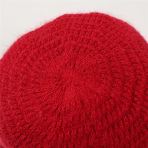 Makroaufnahme der roten Strickmütze zeigt die dicke Wollstruktur und die Nähte