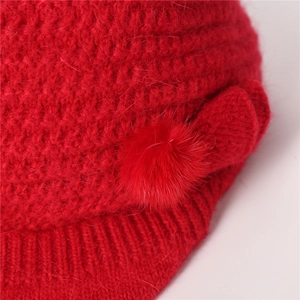 Nahaufnahme der roten Strickstruktur und des weichen Bommels an dieser Wintermütze