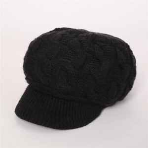 Detalle de textura de punto trenzado negro y ala acanalada en gorra de lana de mujer