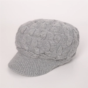 Detalle de gorra de punto gris claro con textura de trenzas gruesas y visera corta