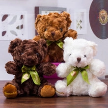 Close-up of three plush teddy bears in brown and white with decorative green ribbons