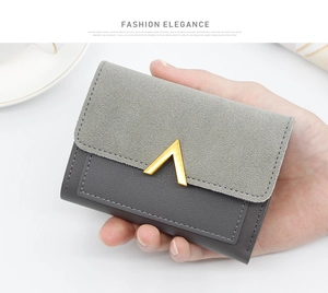 Detailed shot of a compact grey trifold wallet with gold V-clasp held in hand