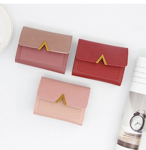 Close-up of three-fold women's mini wallets in wine red and pink with gold V-hardware