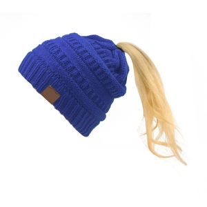 Dettaglio del berretto in maglia blu reale con foro per coda di cavallo e patch
