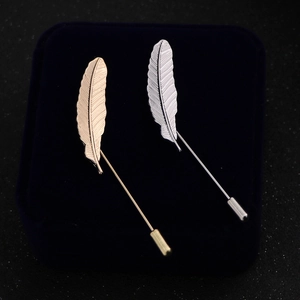 Elegant gold and silver feather lapel pins with detailed texture on blue velvet