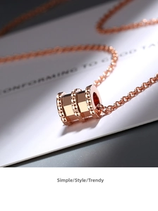 Macro shot of rose gold necklace featuring a triple-ring cylinder pendant with faceted edges
