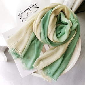 Green and beige gradient cotton linen scarf with tassels on a minimalist table