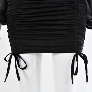 Close-up of black bodycon dress with lettuce edge hem and drawstring ruched details