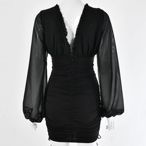 Detail view of back side mesh sleeves and ruched texture on black mini dress