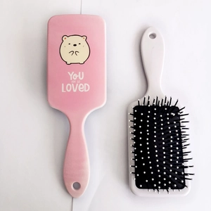 Close-up of cute cartoon bear plastic paddle hair brushes with pink and white finish