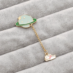 Detail of enamel planet and rabbit brooch set with gold chain on velvet