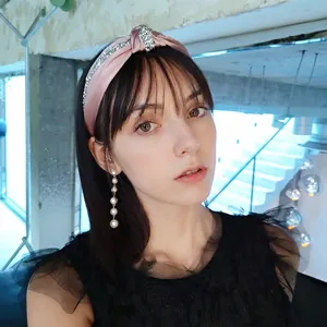 Pink satin knotted headband with rhinestone detail and pearl drop earrings on a model