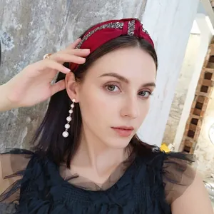 Sparkly rhinestone knotted headband in red satin paired with long pearl drop earrings