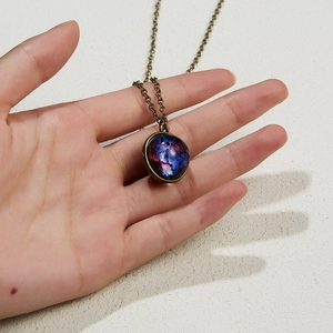 Antique bronze necklace with a luminous round galaxy nebula glass pendant in hand