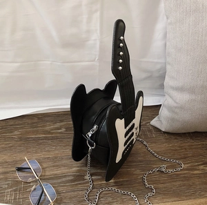 Detail of guitar shaped crossbody bag with black white leather and silver chain strap