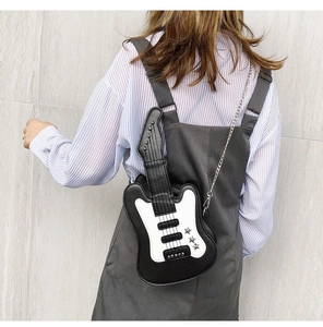 Detail of guitar-shaped shoulder bag with silver star accents and chain strap on a model