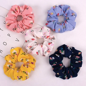 Detailed view of 5 floral scrunchies in pink, blue, yellow, navy, and beige fabric