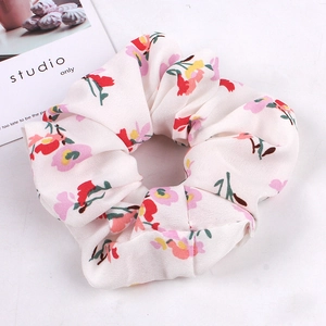 Detailed view of white scrunchie with pink and yellow floral patterns on soft fabric