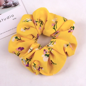 Detail of yellow fabric scrunchie with purple floral patterns and soft texture