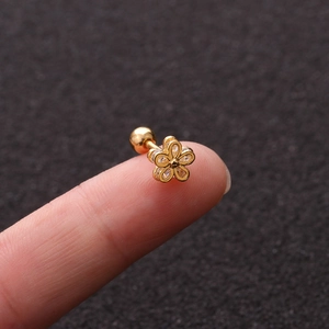 Golden flower screw back earring with cubic zirconia crystals shown on a fingertip