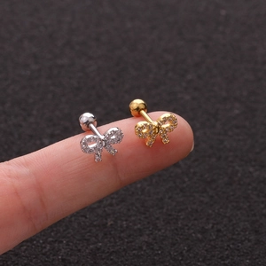 Macro shot of silver and gold bow stud earrings with inlaid crystals on fingers