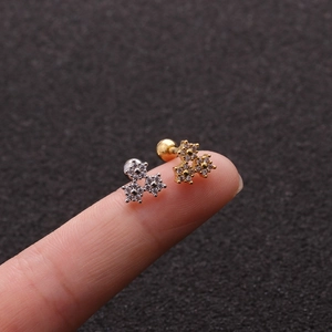 Macro shot of gold and silver flower stud earrings with zircons on fingertips