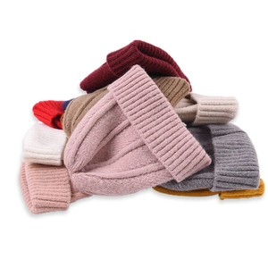 Stack of colorful ribbed knit beanies for toddlers and parents in various warm colors
