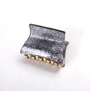Detail of acrylic hair claw clip with silver glitter surface and golden metal teeth