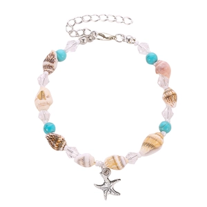 Detail of bohemian starfish charm and natural seashell beads on a summer beach anklet