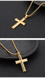 Gros plan détaillé du pendentif croix dorée texturée avec sa chaîne sur fond noir