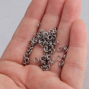 Close-up of silver stainless steel jump rings in palm showing size and metal shine