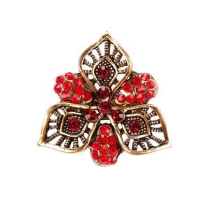 Vintage bronze flower brooch with sparkling red rhinestones on a white background