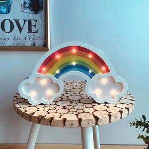 Detail of creative rainbow cloud LED wall light on rustic wood slice side table decoration