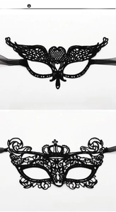Detail view of heart and crown patterns on black lace masquerade eye masks with ribbons