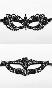 Detail of two black lace masquerade masks with intricate cutout patterns and silk ribbons