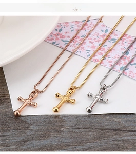 Detailed view of polished cross pendants in rose gold, gold, and silver with box chains