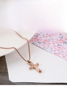Detail of rose gold box chain and cross pendant with polished metal sphere design