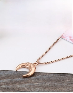 Close-up of a gold crescent moon pendant with striped texture on a sleek box chain