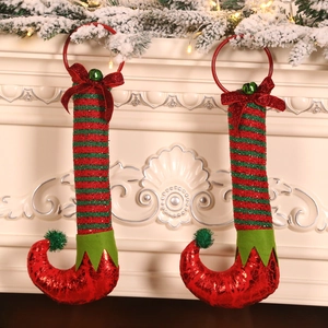 Pair of Christmas elf leg door wreaths with sequins and bells on a cozy fireplace mantel