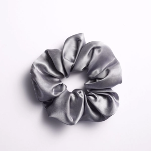 Glossy silver satin scrunchie with elegant folds for ponytail or bun hairstyles