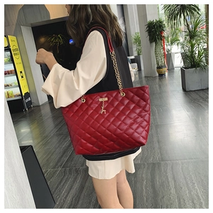 Detail of red quilted chain tote bag featuring a gold deer charm and large capacity