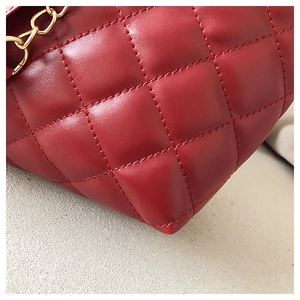 Close-up of red quilted leather bag with gold chain and refined stitching details