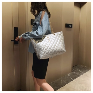 Silver quilted tote bag with gold chain strap shown on model for capacity reference